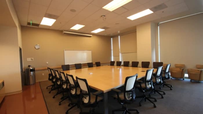 A boardroom set with a long conference table, office chairs and a whiteboard
